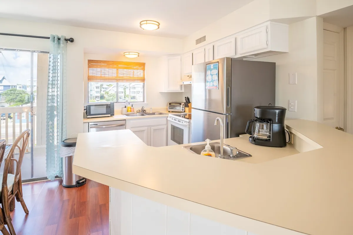 This image showcases a kitchen island with sleek stainless steel appliances and a window offering a view outside. The space is styled for comfort and sociability, with the island serving as a central gathering point for meal prep, casual breakfasts, or sharing a drink.