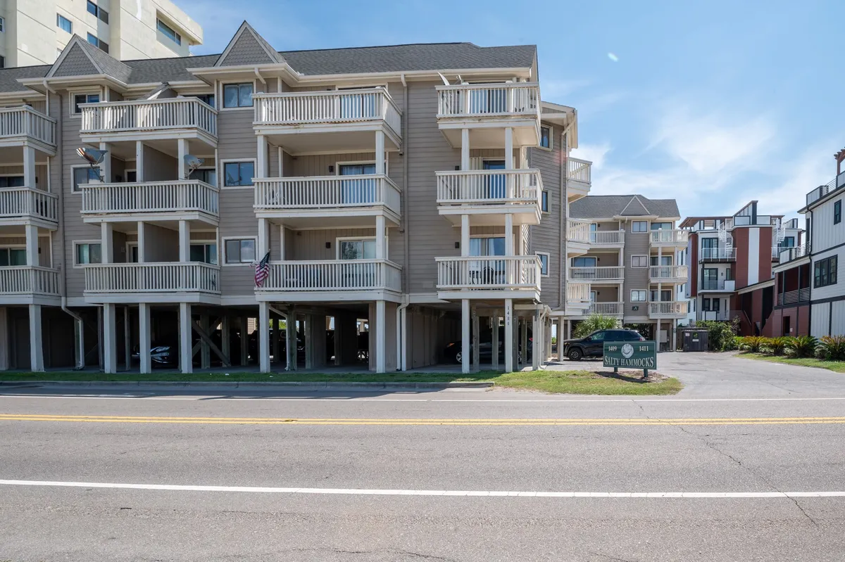 The exterior of the building highlights multiple balconies, inviting signage, and distinctive architecture. Palm trees frame the entrance, suggesting easy access to nearby attractions and the ocean beyond.