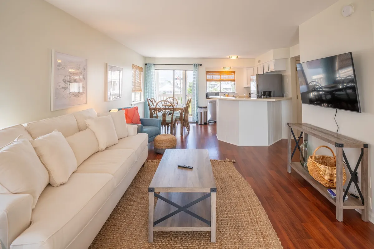 A cozy, inviting living room with a sofa, dining table, television, and large window offering another angle on the ocean views. The space is arranged for family gatherings, movie nights, or meals, creating a sense of warmth and togetherness.