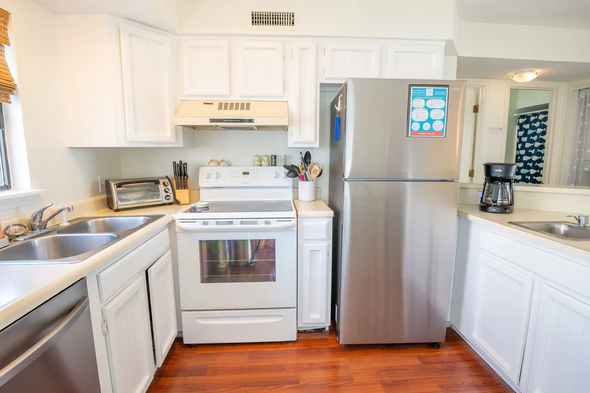 Here, a functional kitchen features a stainless steel refrigerator, white cabinetry, and modern appliances. The design is bright, practical, and ready for hosting or preparing family meals.